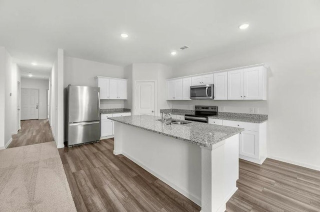 kitchen with a sink, stainless steel appliances, dark wood finished floors, and white cabinetry