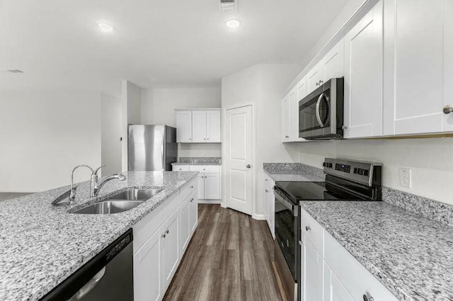 kitchen featuring light stone counters, appliances with stainless steel finishes, dark wood-style floors, white cabinetry, and a sink