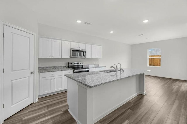 kitchen with dark wood-style floors, light stone countertops, a sink, stainless steel appliances, and white cabinets