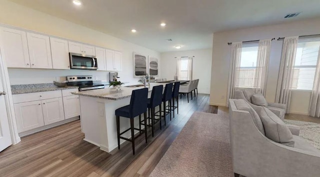 kitchen featuring visible vents, appliances with stainless steel finishes, a kitchen island with sink, and white cabinetry