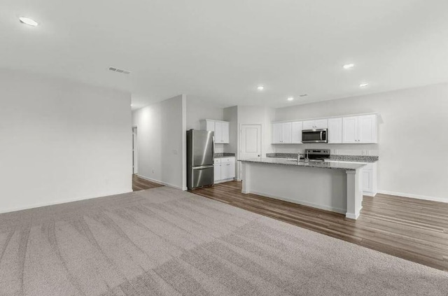 kitchen with a kitchen island with sink, open floor plan, recessed lighting, appliances with stainless steel finishes, and white cabinets