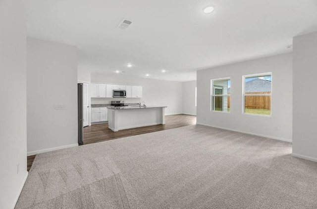 unfurnished living room with recessed lighting, visible vents, baseboards, and carpet