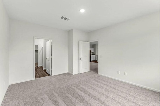 unfurnished bedroom featuring visible vents, carpet floors, baseboards, and a spacious closet