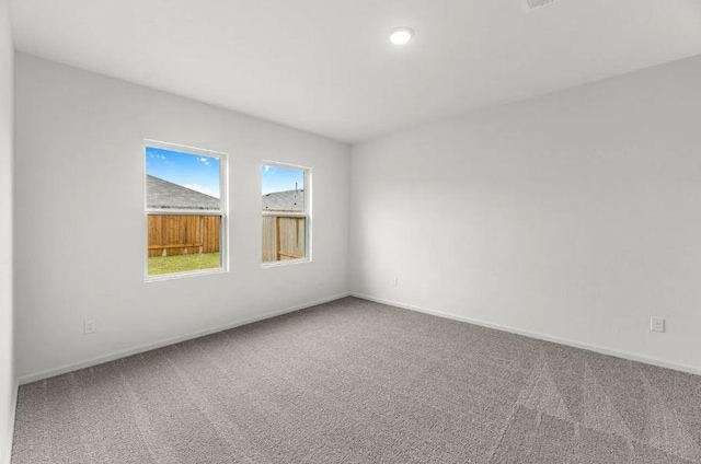 carpeted spare room featuring baseboards