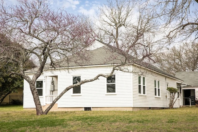 view of side of property featuring a yard and a shingled roof