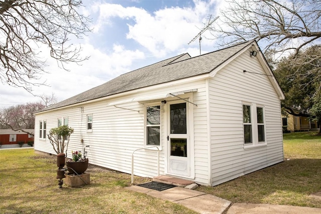 rear view of property with a yard and a shingled roof