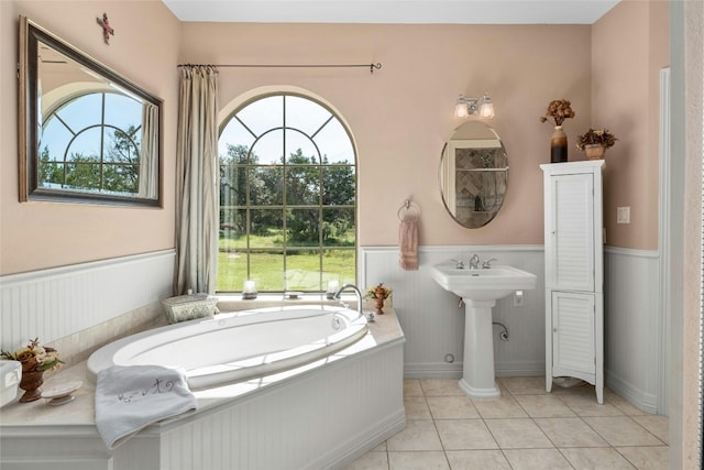 bathroom with tile patterned floors, a garden tub, and wainscoting