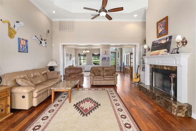 living area with wood finished floors, visible vents, a premium fireplace, a towering ceiling, and crown molding