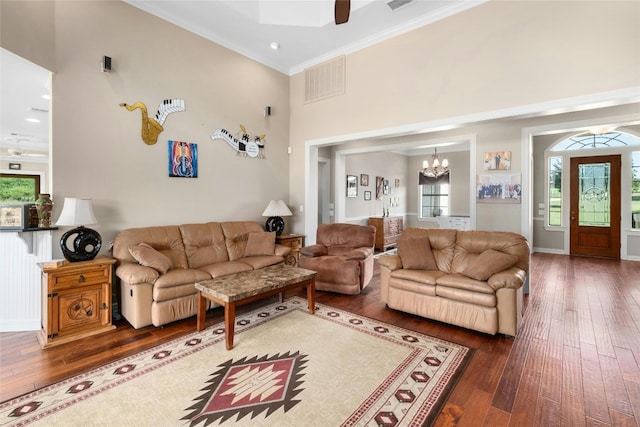 living area featuring hardwood / wood-style floors, visible vents, a towering ceiling, and ornamental molding