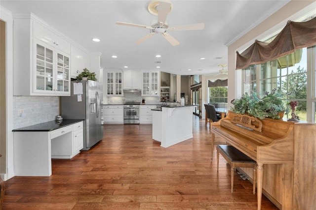 kitchen with dark countertops, glass insert cabinets, stainless steel appliances, dark wood-style floors, and white cabinetry