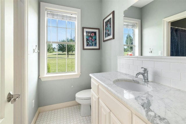 bathroom featuring a wealth of natural light, toilet, vanity, and baseboards