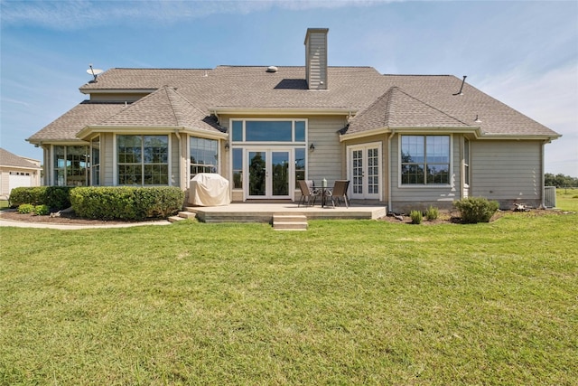 back of property with french doors, a lawn, roof with shingles, and a chimney