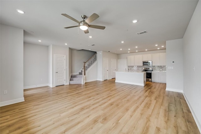 503 Emory Crossing Blvd, Hutto, TX 78634 - unfurnished living room featuring stairs, recessed lighting, baseboards, a ceiling fan, and light wood-type flooring