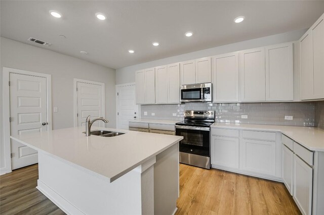 503 Emory Crossing Blvd, Hutto, TX 78634 - kitchen featuring stainless steel appliances, a sink, decorative backsplash, light wood-style flooring, and recessed lighting