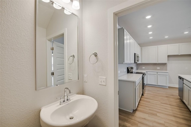 503 Emory Crossing Blvd, Hutto, TX 78634 - bathroom featuring a sink, wood finished floors, recessed lighting, a textured wall, and tasteful backsplash