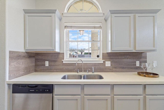 kitchen with stainless steel dishwasher, light countertops, backsplash, and a sink