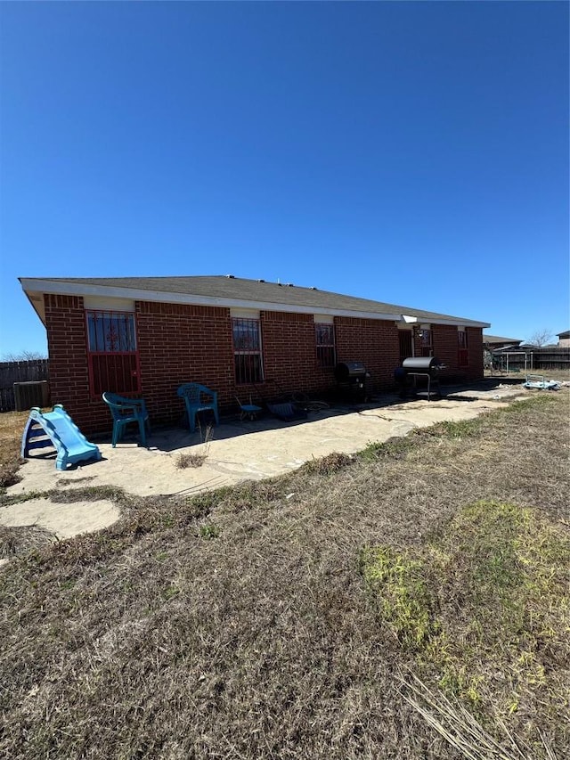 back of property featuring a patio, brick siding, and fence