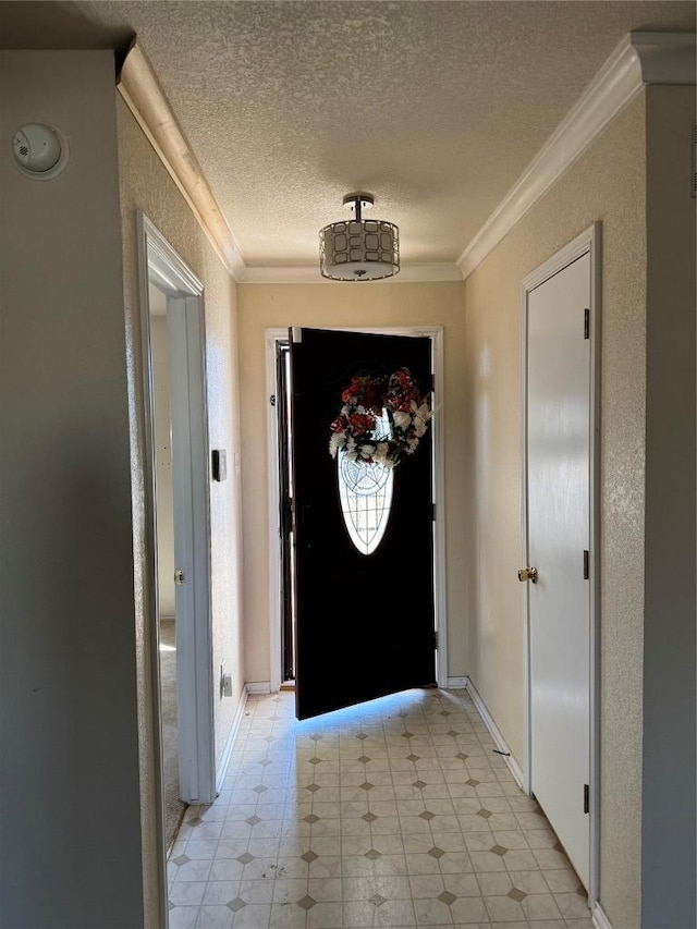 entryway featuring baseboards, a textured ceiling, ornamental molding, and a textured wall