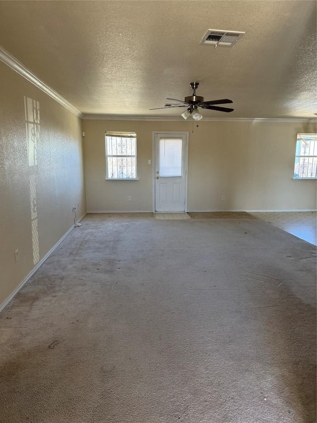 unfurnished room with crown molding, light colored carpet, visible vents, and a textured ceiling