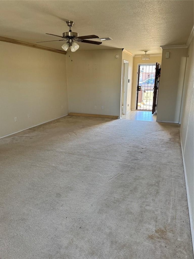 spare room with visible vents, ornamental molding, a textured ceiling, carpet floors, and ceiling fan