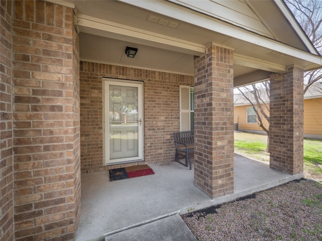 entrance to property with brick siding and covered porch