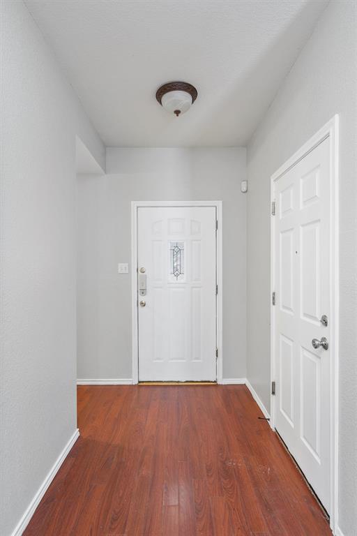 doorway featuring wood finished floors and baseboards