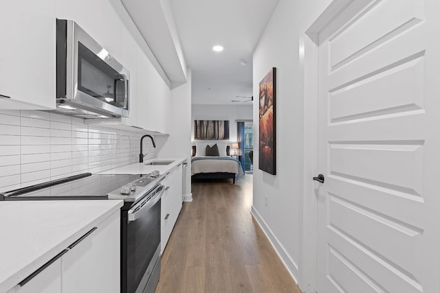 2220 Webberville Rd Unit 225, Austin, TX 78702 - kitchen with stainless steel appliances, a sink, white cabinets, light wood-style floors, and light countertops
