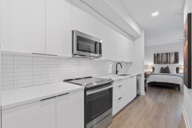 2220 Webberville Rd Unit 225, Austin, TX 78702 - kitchen with stainless steel appliances, a sink, modern cabinets, white cabinets, and recessed lighting
