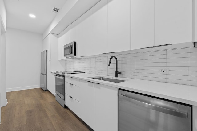 2220 Webberville Rd Unit 225, Austin, TX 78702 - kitchen featuring appliances with stainless steel finishes, a sink, white cabinetry, light countertops, and dark wood finished floors