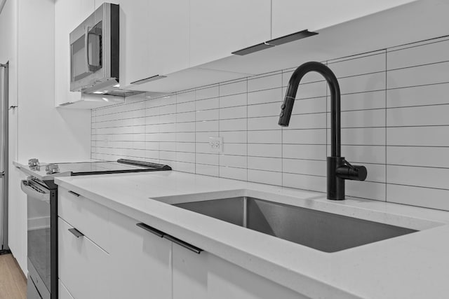 2220 Webberville Rd Unit 225, Austin, TX 78702 - kitchen featuring range with electric cooktop, a sink, stainless steel microwave, and white cabinetry