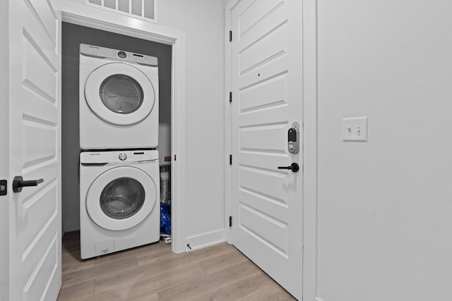2220 Webberville Rd Unit 225, Austin, TX 78702 - washroom with stacked washer and clothes dryer, light wood-type flooring, and baseboards