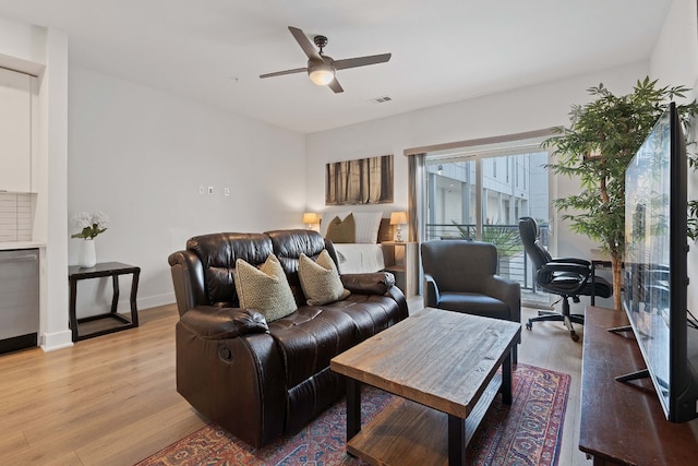 living area with visible vents, baseboards, ceiling fan, and light wood finished floors