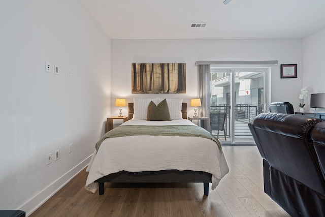 bedroom with visible vents, wood finished floors, baseboards, and access to exterior