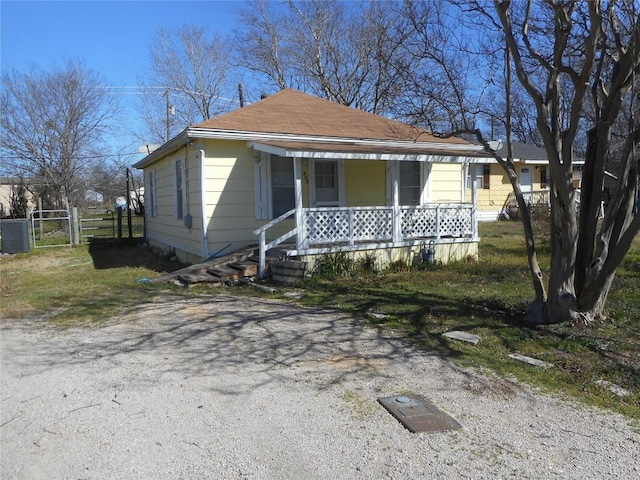 view of front of house with driveway, a gate, central AC, fence, and covered porch