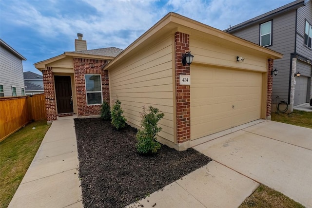 view of front of house featuring fence, concrete driveway, an attached garage, brick siding, and a chimney