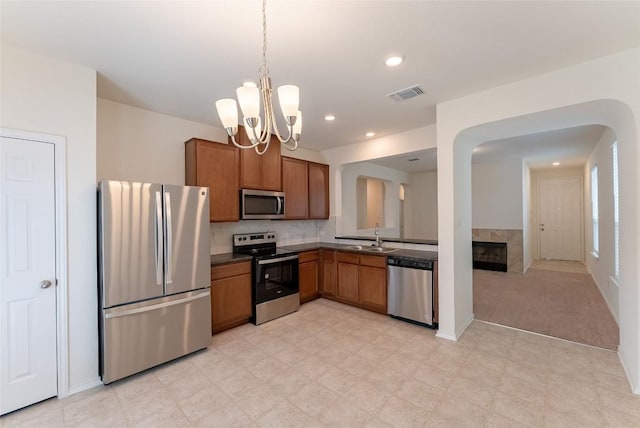 kitchen featuring dark countertops, visible vents, brown cabinetry, stainless steel appliances, and a sink