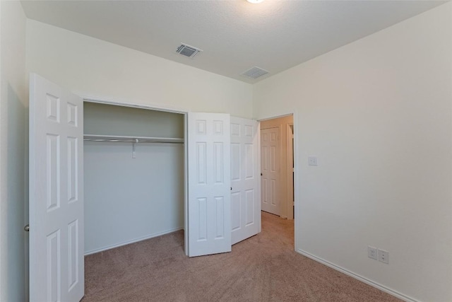 unfurnished bedroom featuring carpet flooring, visible vents, and a closet