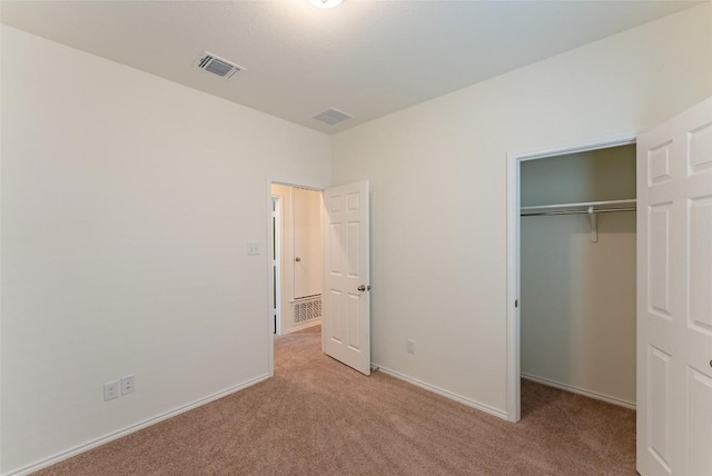 unfurnished bedroom with baseboards, visible vents, light carpet, and a closet