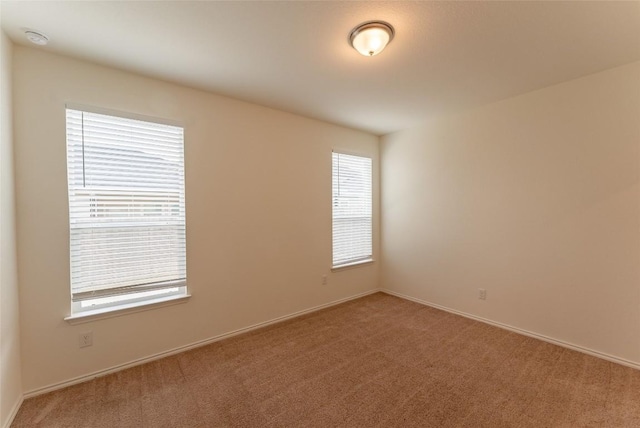 spare room with light colored carpet and baseboards