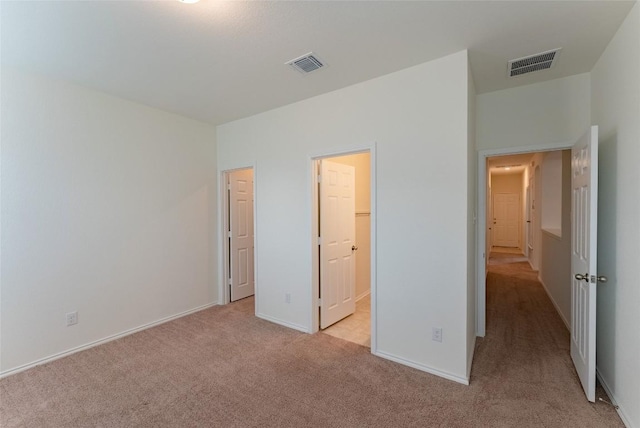 unfurnished bedroom featuring visible vents, baseboards, and light colored carpet