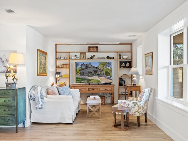 sitting room featuring light wood finished floors, visible vents, and baseboards