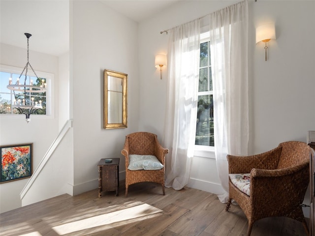 living area with an upstairs landing, a notable chandelier, baseboards, and wood finished floors