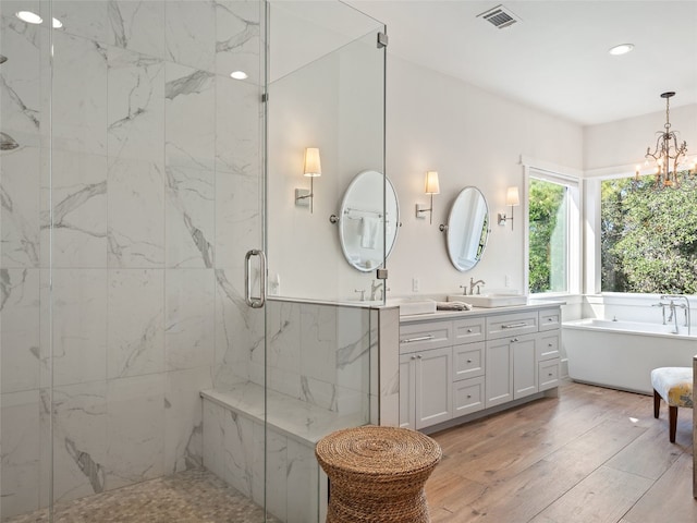 bathroom featuring wood finished floors, visible vents, a marble finish shower, a soaking tub, and a sink