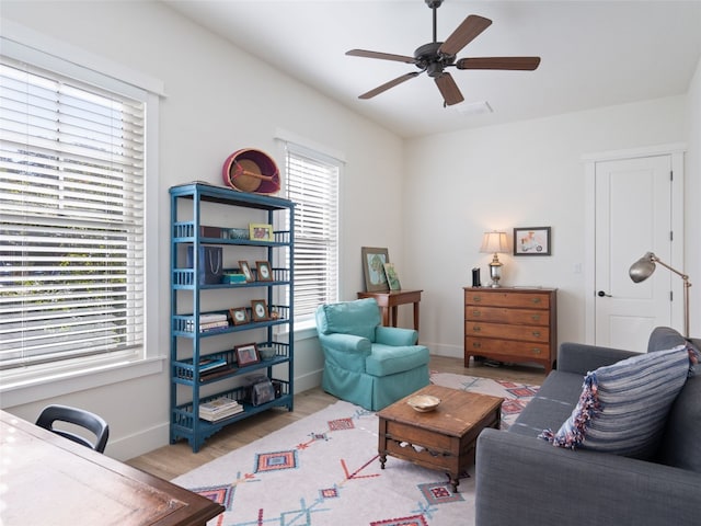 living room with visible vents, baseboards, a ceiling fan, and wood finished floors