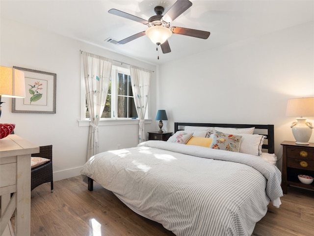 bedroom featuring visible vents, baseboards, wood finished floors, and a ceiling fan