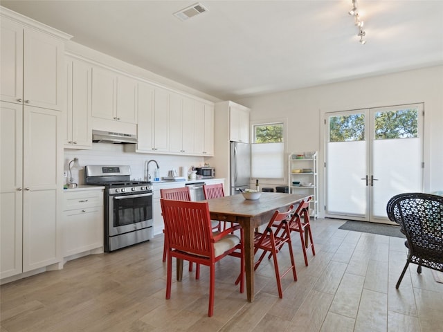 kitchen with visible vents, light wood-type flooring, under cabinet range hood, french doors, and appliances with stainless steel finishes