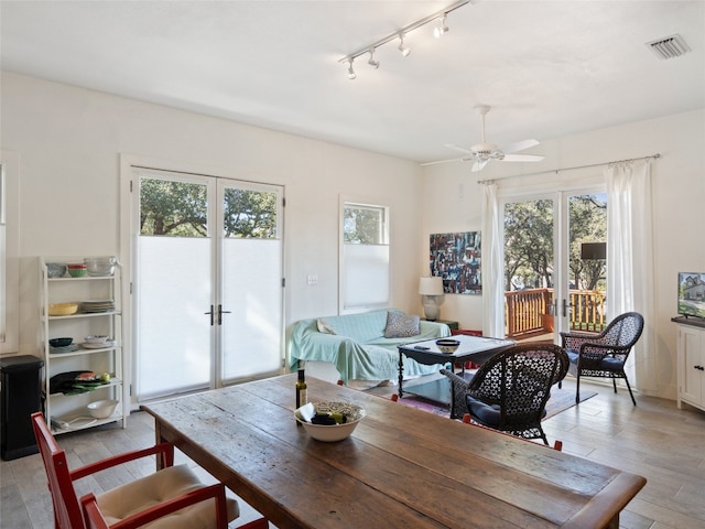 dining room featuring visible vents, light wood-style flooring, track lighting, a ceiling fan, and french doors