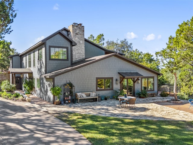 back of property with a patio, a lawn, and a chimney