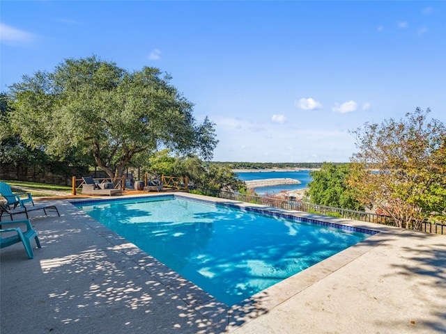 view of pool featuring a patio area, a fenced in pool, fence, and a water view