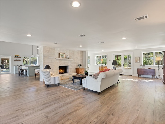 living room featuring visible vents, light wood-style floors, and a fireplace